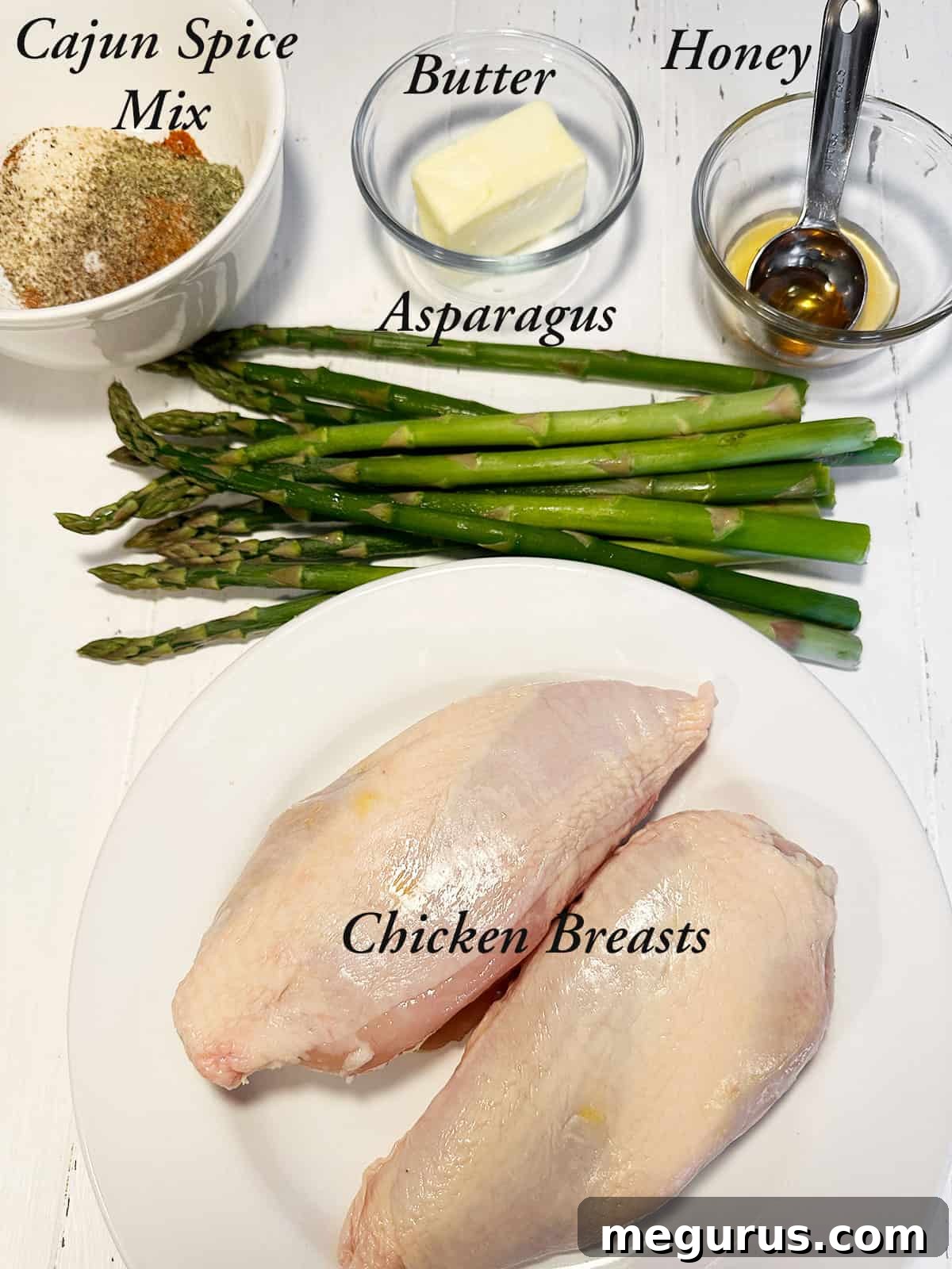 Ingredients to make cajun chicken, including spices, chicken, honey, and butter.