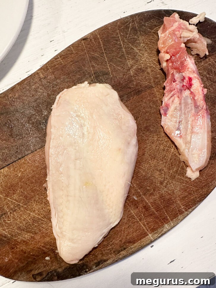 Removing the bone from the chicken breast with a sharp knife.