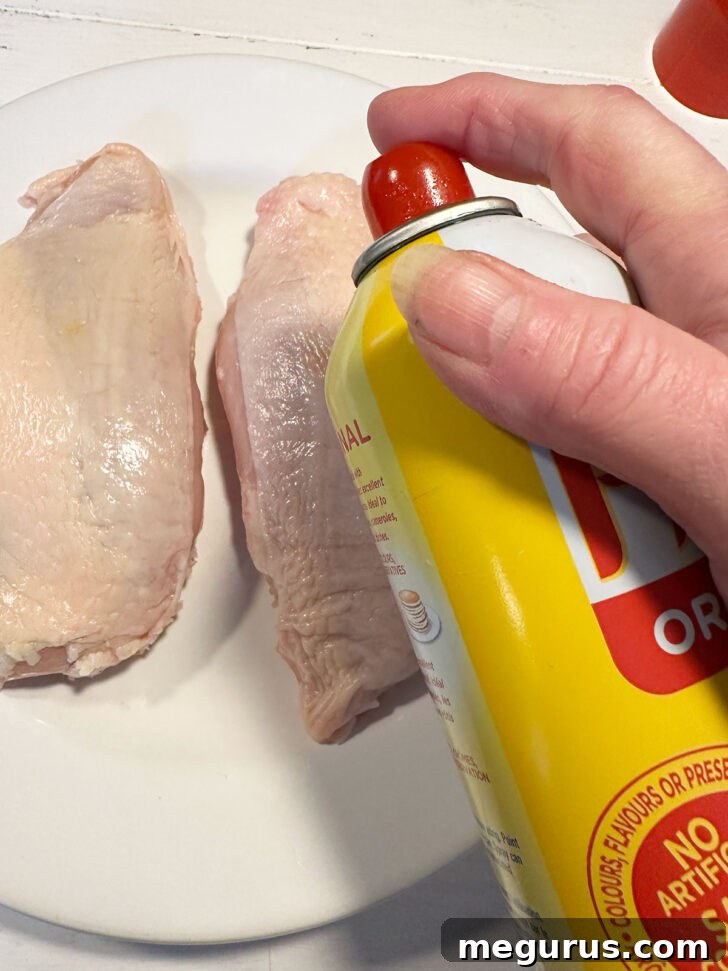 Spraying the chicken breast with cooking spray before seasoning.