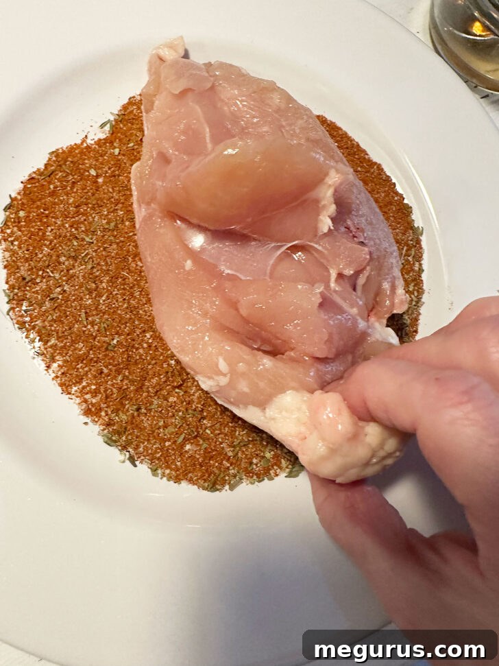 Dipping the chicken breast generously in the homemade Cajun spice mix.