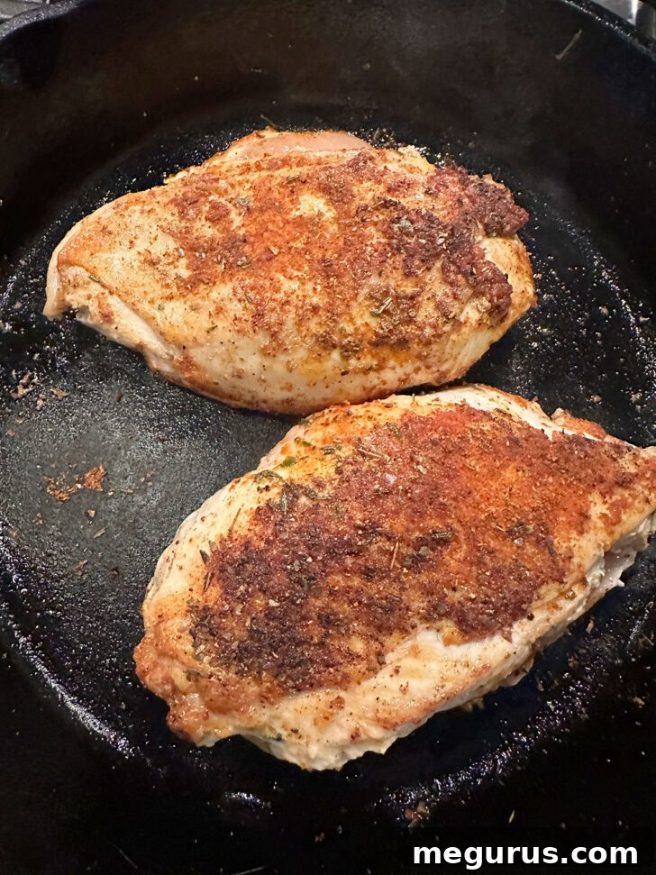 Chicken after being flipped in the skillet, showing a beautiful blackened crust.