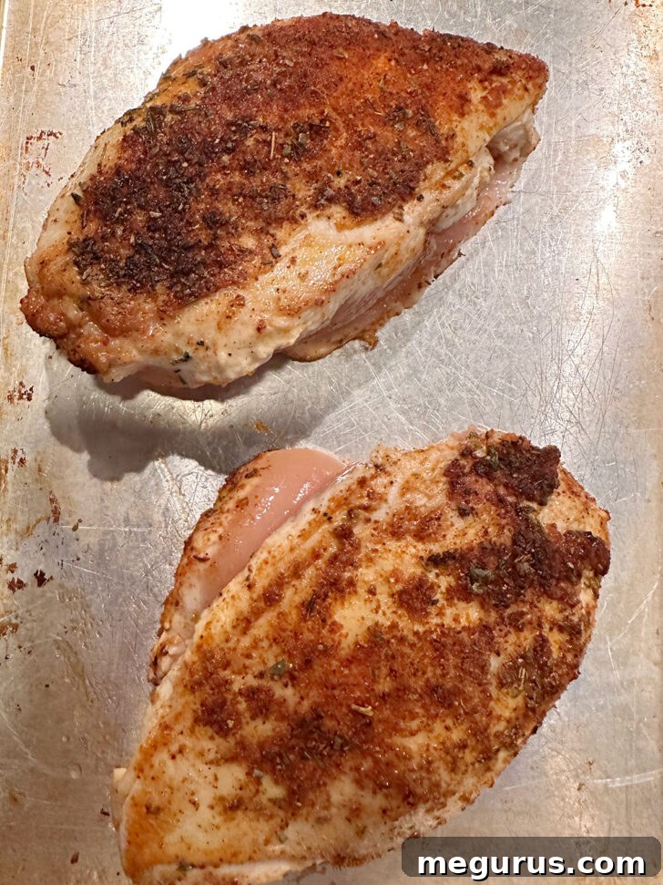 Partially cooked chicken on a baking sheet, ready to finish in the oven.