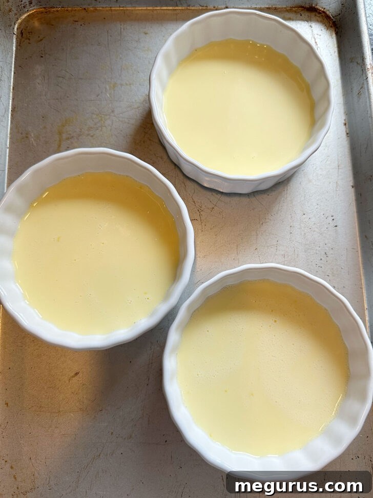 Custard poured in ramekins, placed in a water bath, ready to bake.