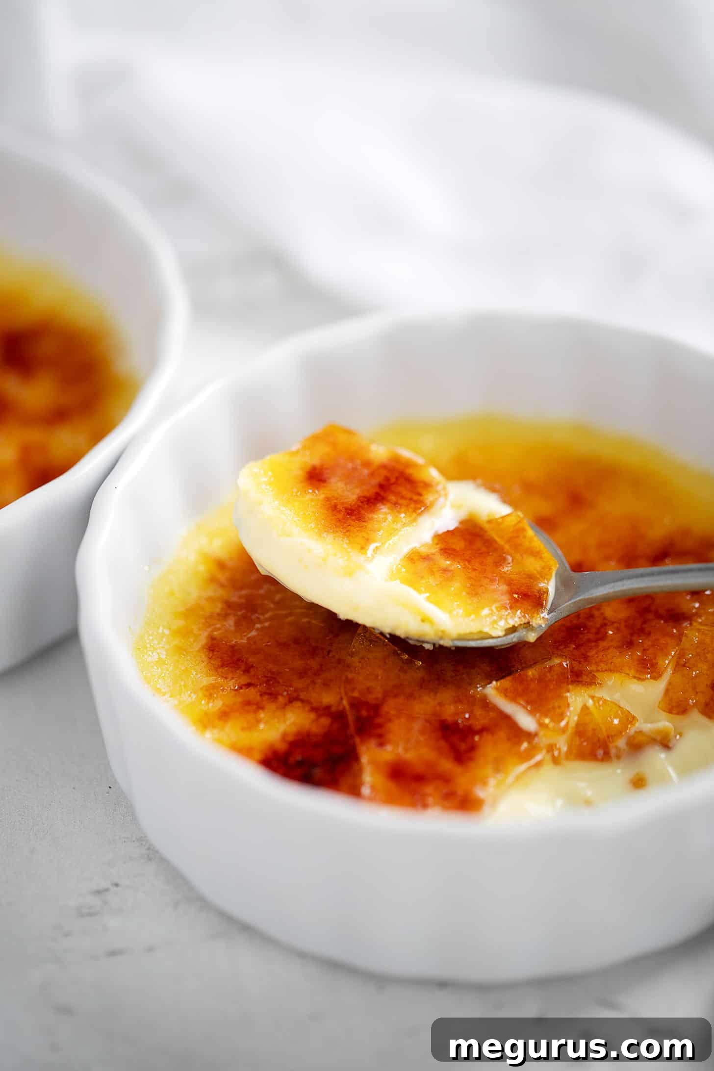 Close-up of a Lemon Creme Brulee in a ramekin with a spoon digging in.