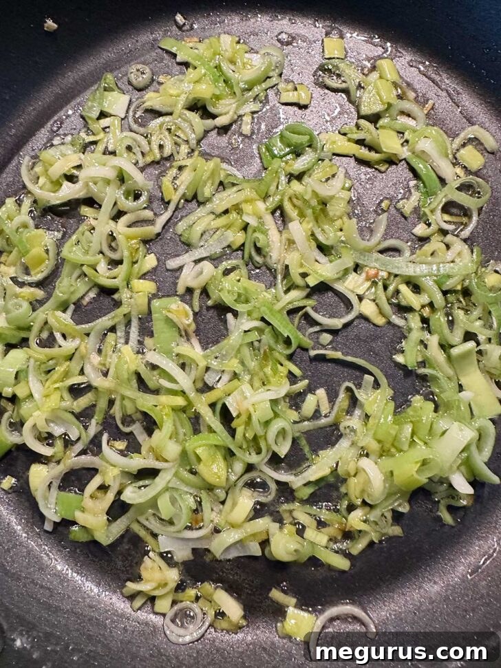 Softened leeks resting in a skillet after cooking.