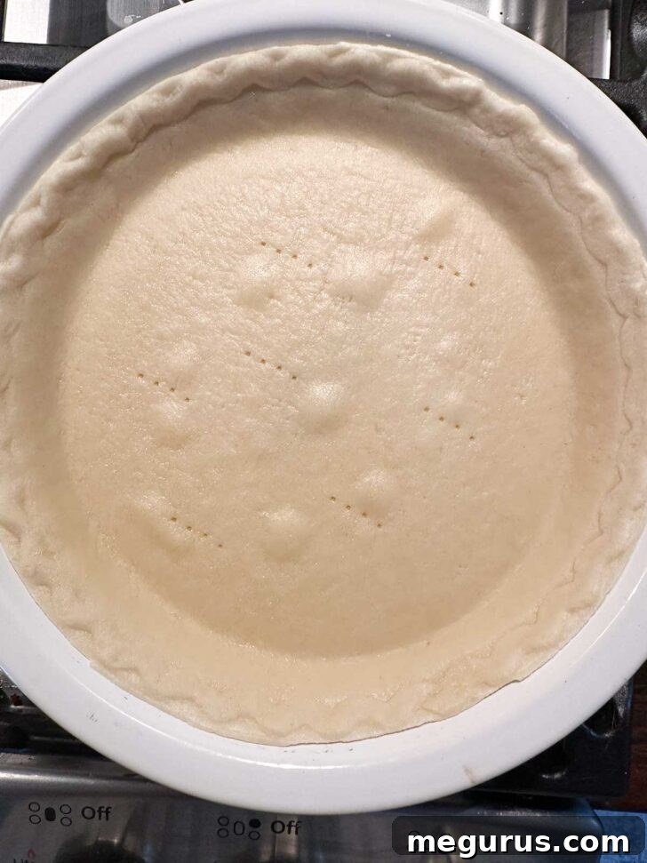 A pie crust after being par-baked in the oven, showing a light golden color.