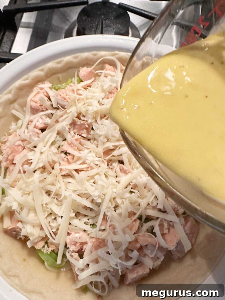 Pouring the creamy egg custard mixture into the pie shell, over the salmon and leeks.