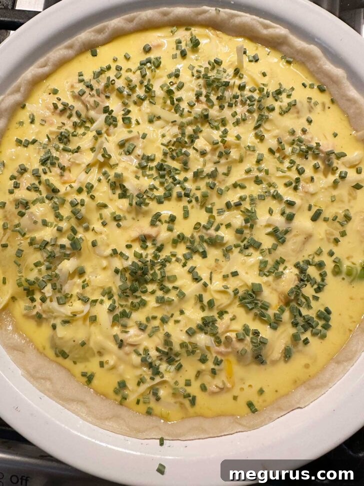Sprinkling diced chives over the top of the liquid quiche custard.