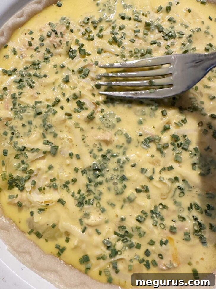 Gently pressing the chives into the custard with a fork to moisten them before baking.