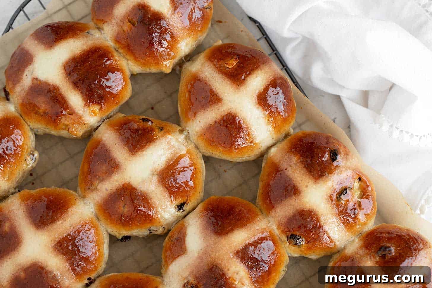Traditional hot cross buns on cooling rack, freshly baked and glazed.