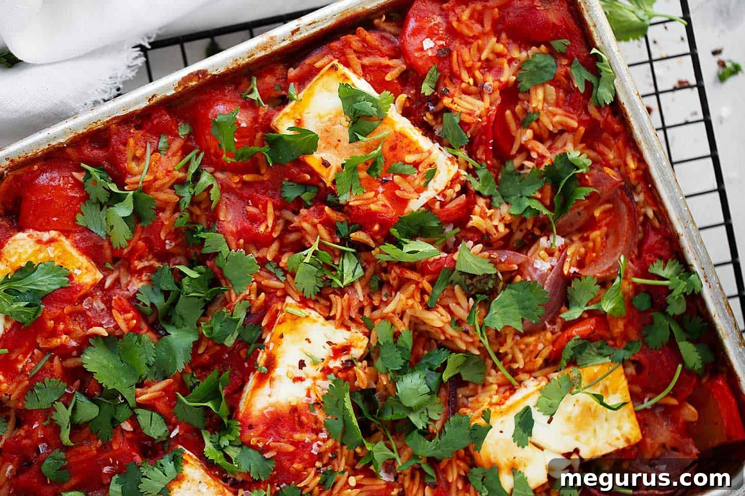 Sheet pan tomato orzo in pan, garnished with fresh herbs.