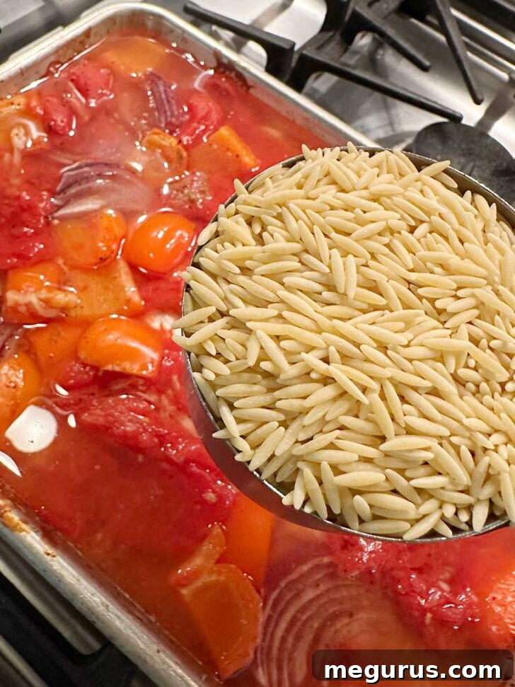 Orzo pasta being added to the sheet pan.