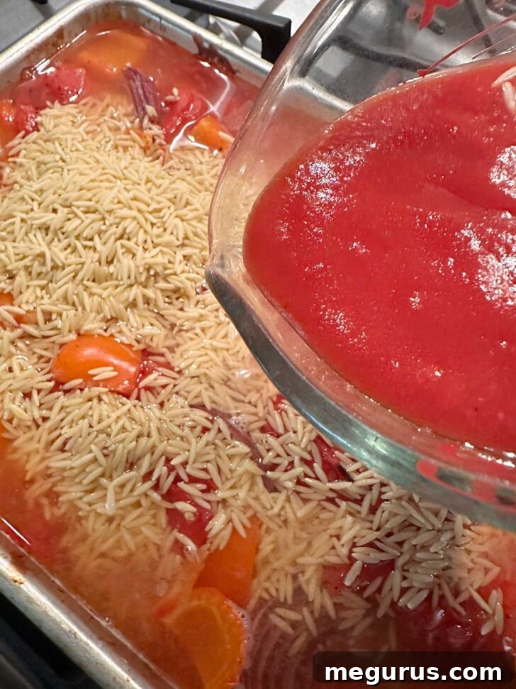 Reserved tomato juices being added to the sheet pan mixture.