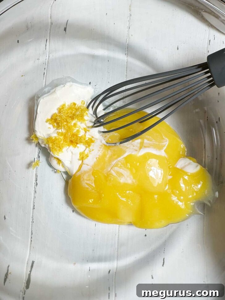 Lemon curd, crème frâiche, and optional lemon zest in a mixing bowl, ready to be combined for the pudding base.