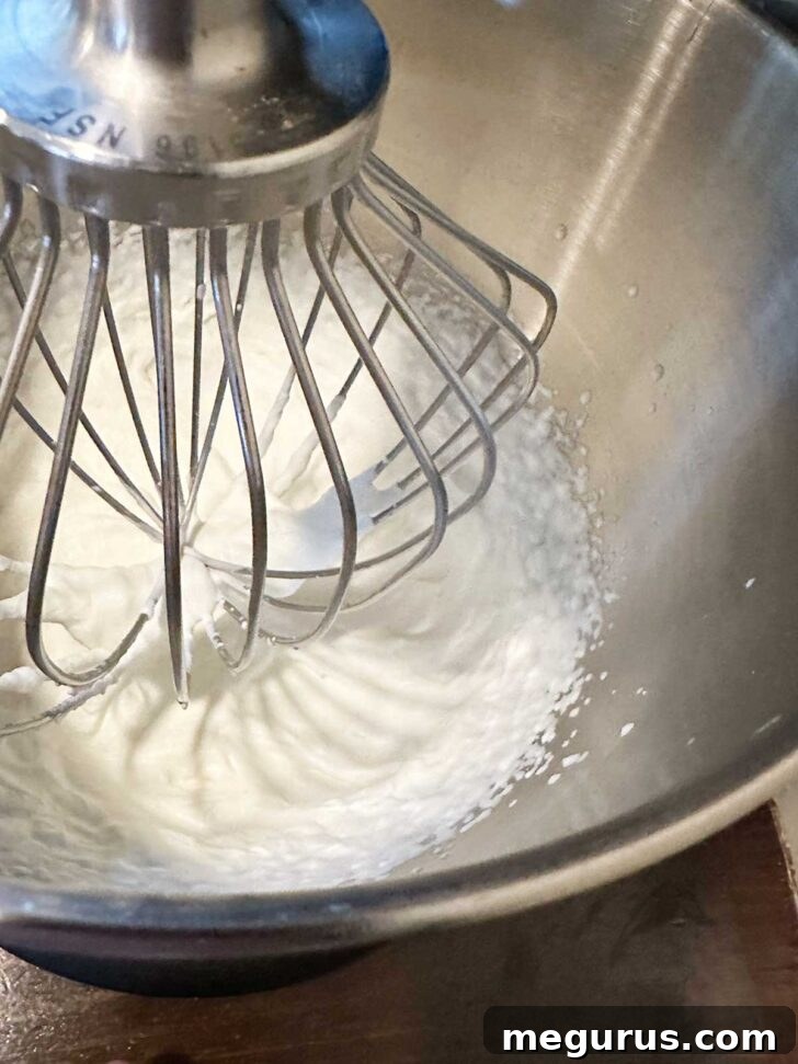 Heavy whipping cream in a mixing bowl, perfectly whipped to soft peaks, ready to be folded into the lemon mixture.