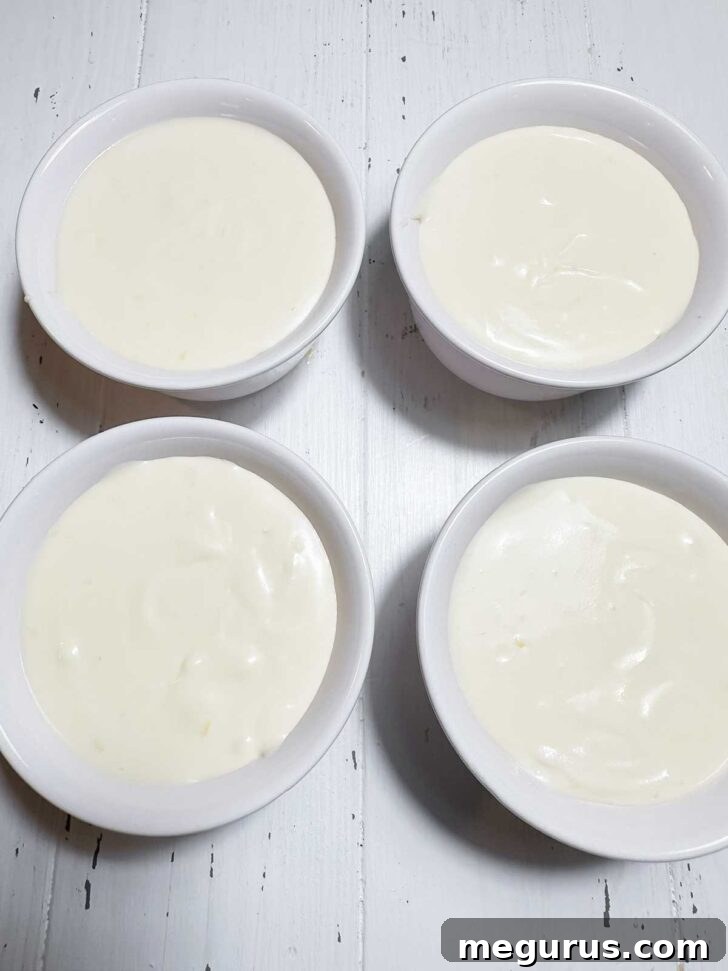 Lemon curd pudding being spooned into individual ramekins, preparing them for chilling and final topping.