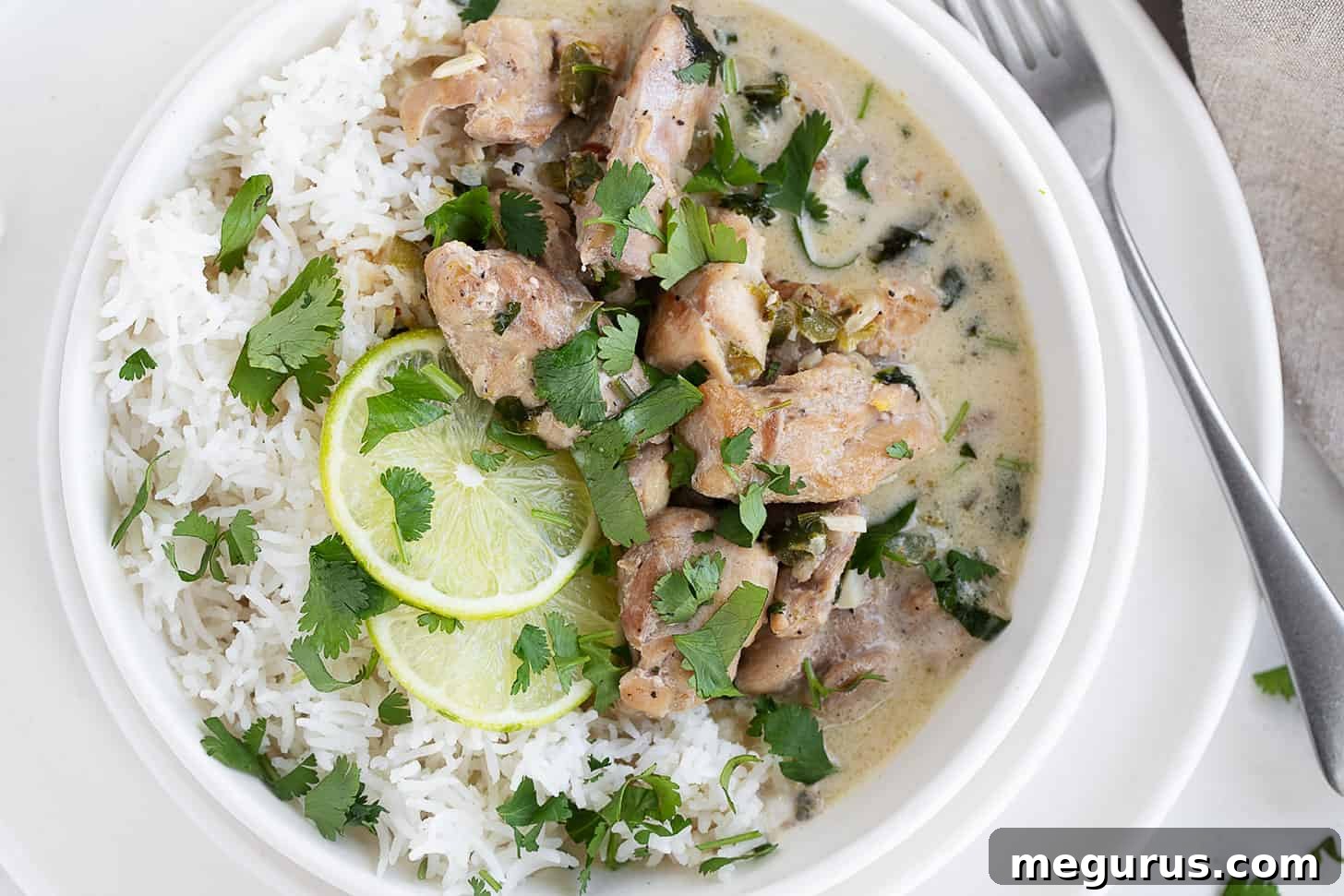 Creamy coconut lime chicken in a bowl over rice, garnished with fresh cilantro.