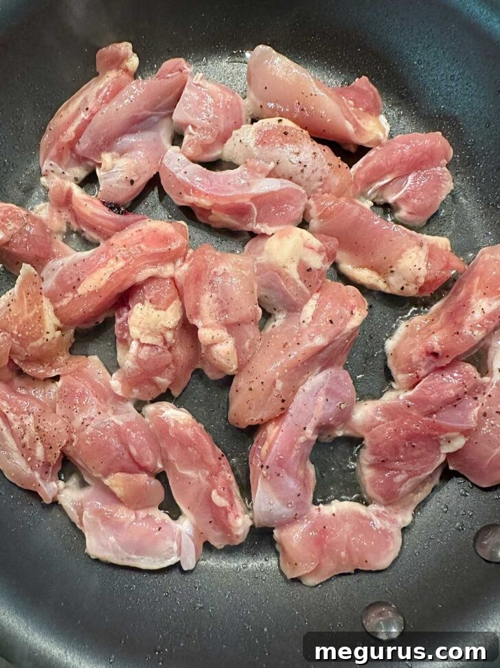 Browning chicken pieces in a hot skillet with oil.