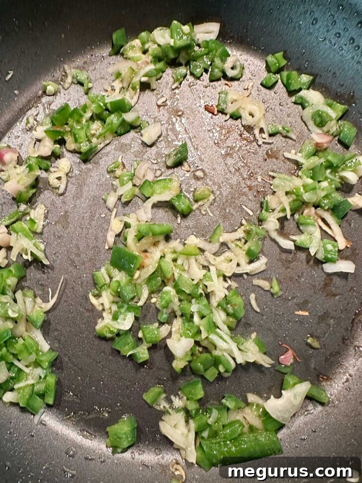 Sautéing diced jalapeño and shallots in a skillet.