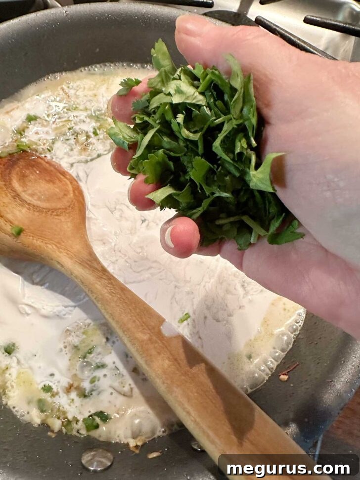 Pouring coconut milk into the skillet with cilantro and aromatics.