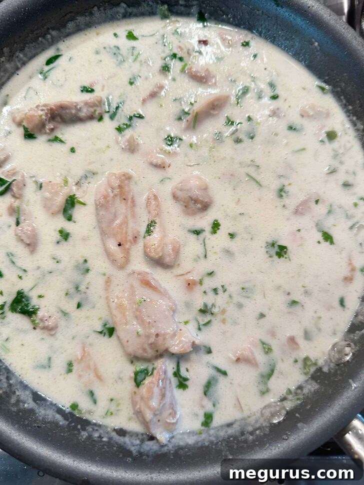Returning the cooked chicken to the skillet with the creamy coconut lime sauce.