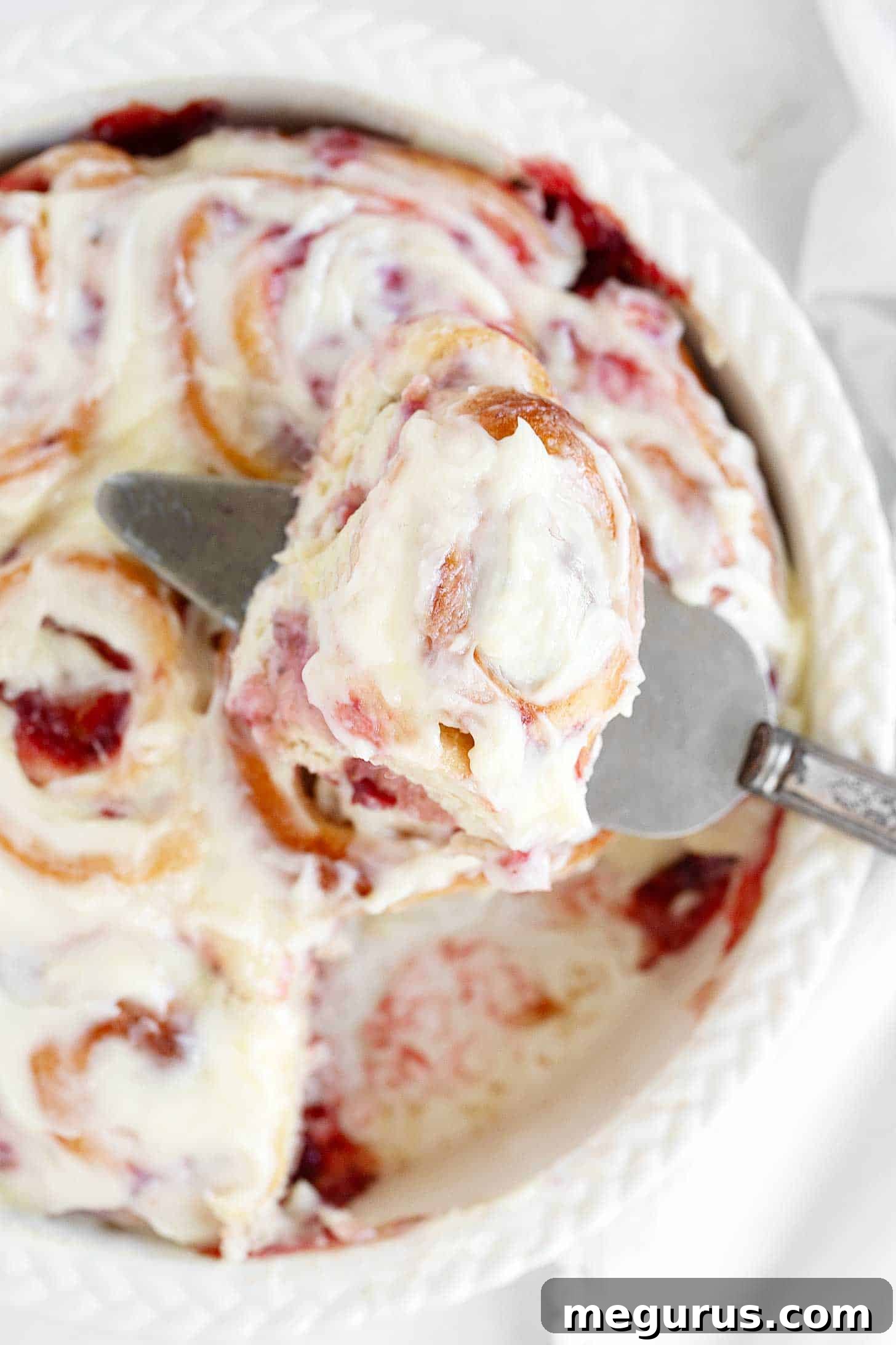 Close up of a pan of baked strawberry cinnamon rolls, still warm from the oven.