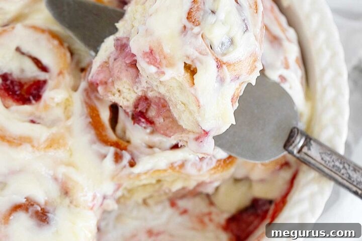Strawberry cinnamon rolls in baking dish with creamy frosting.