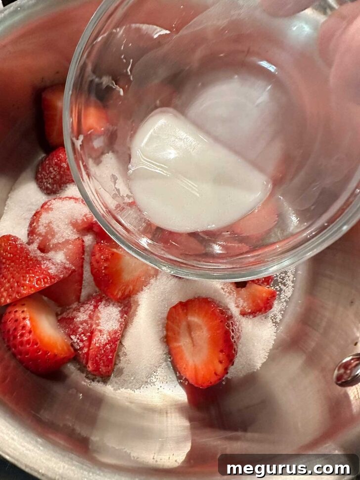 Adding cornstarch slurry to strawberries and sugar in saucepan.