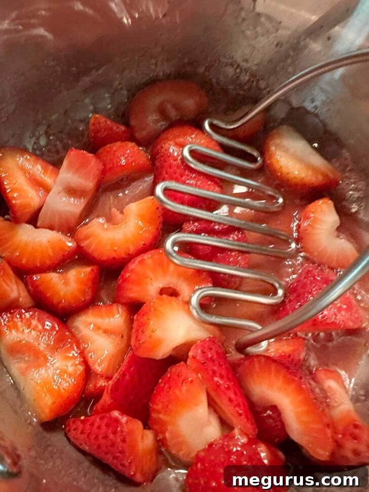 Mashing the strawberries with a potato masher.