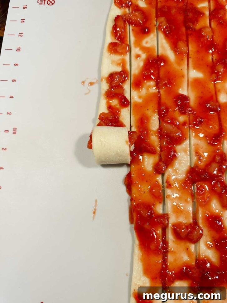 Rolling up the sliced dough and strawberries into rolls.