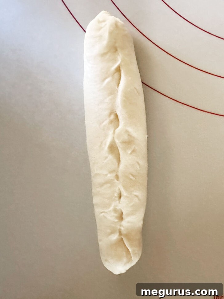 Pinching the seam and ends of the rolled brioche dough to seal it.