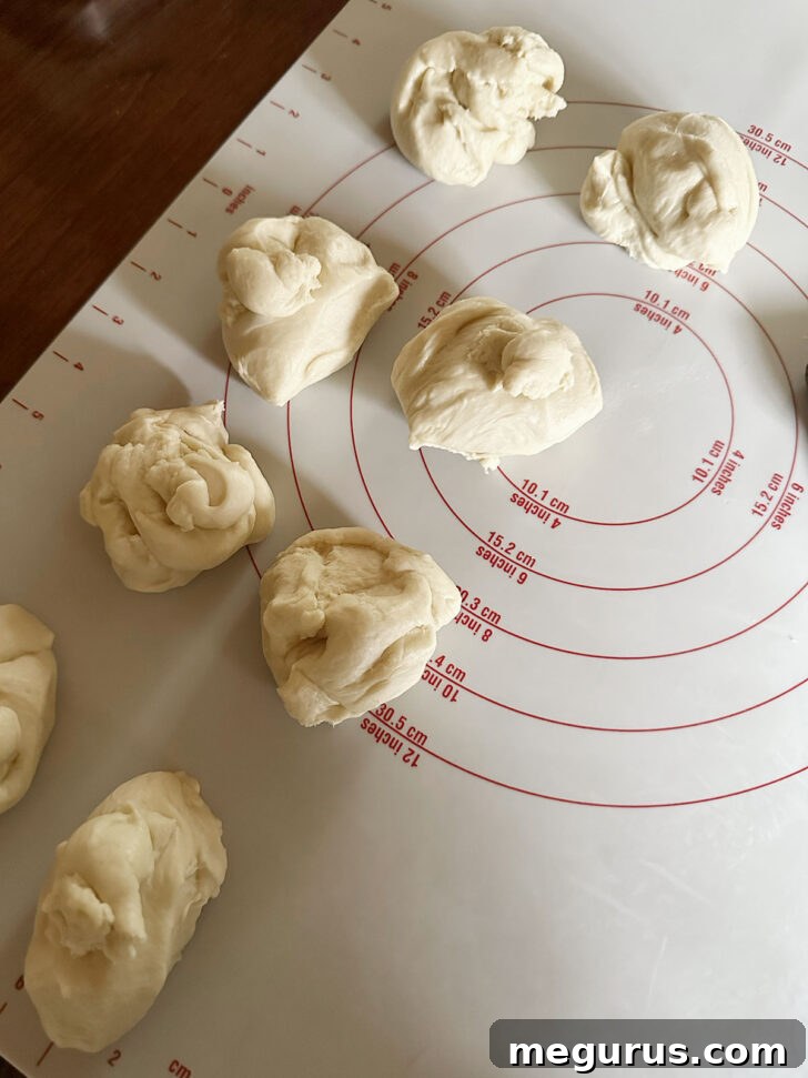 Eight uniformly shaped brioche dough balls resting on a work surface.