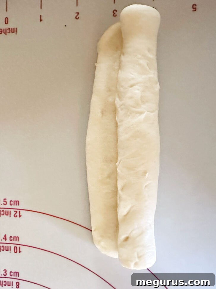 Carefully rolling up the rectangular brioche dough into a log.