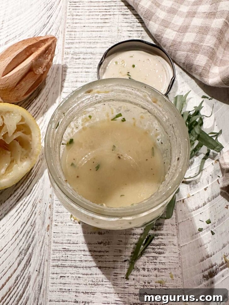 Lemon tarragon vinaigrette after shaking. A small glass jar of lemon tarragon vinaigrette showing a well-emulsified, creamy yellow dressing after being shaken.