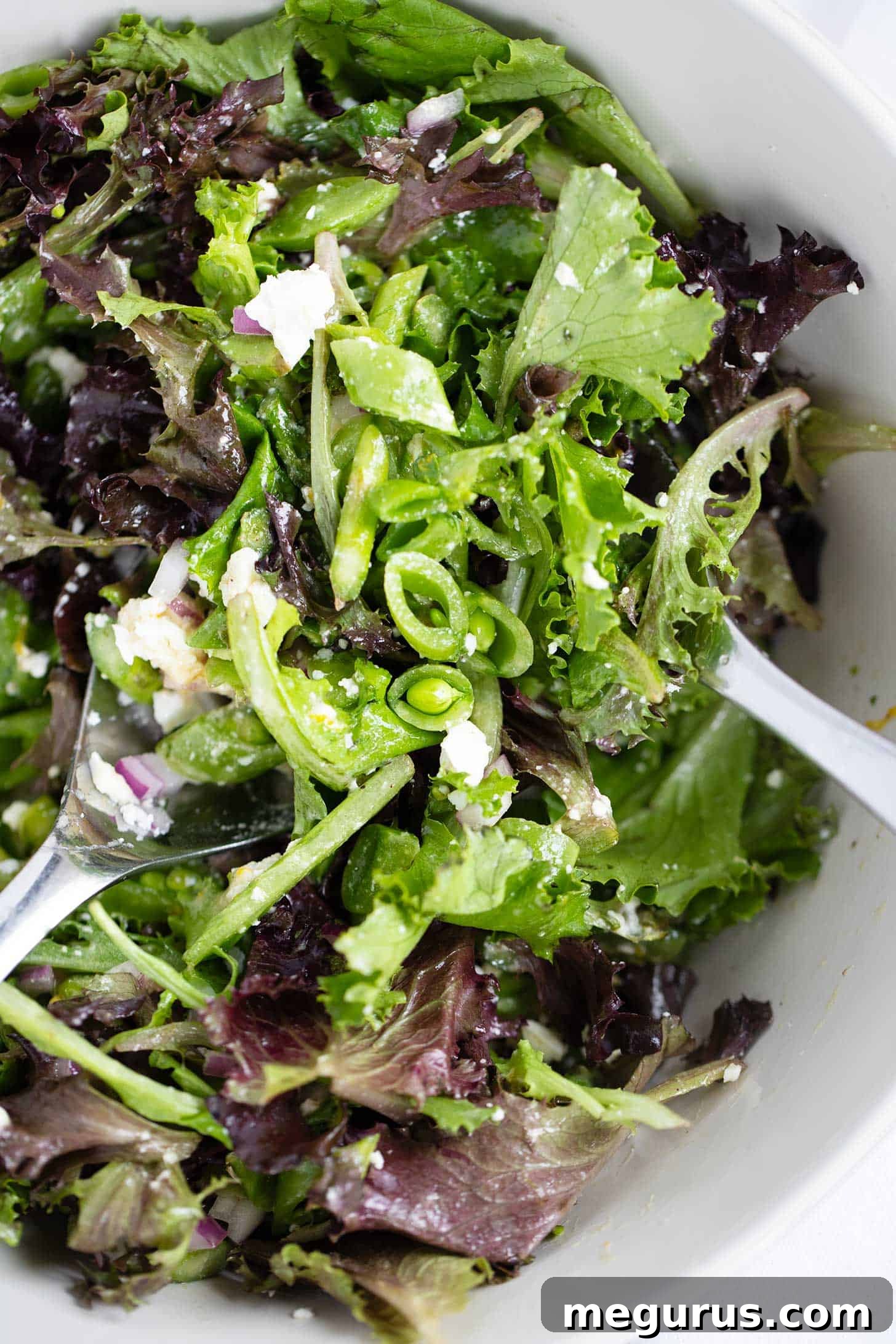 Simple Spring salad in bowl. A beautiful, vibrant bowl of simple spring salad with asparagus, snap peas, red onion, feta, and mixed greens, ready to be served.