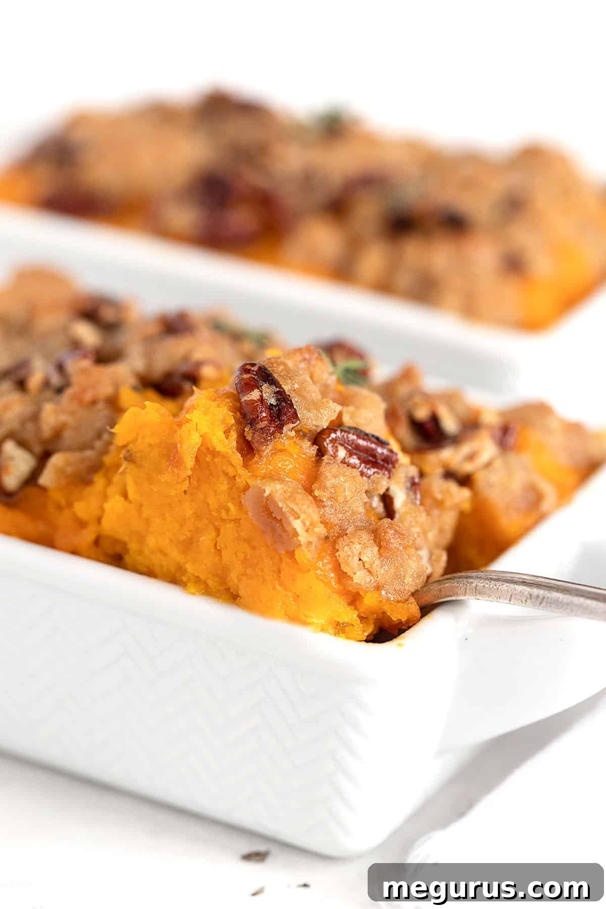 Serving roasted butternut squash casserole with a spoon from a dish.