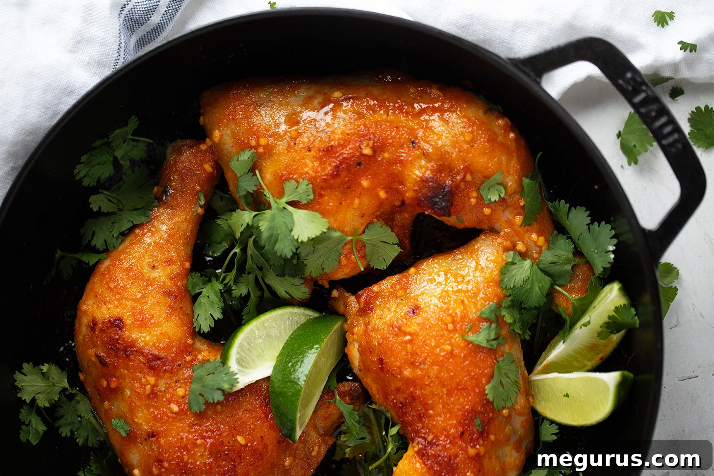 Sriracha glazed chicken legs in a baking dish, perfectly cooked with a rich, glossy sauce, garnished with fresh cilantro.