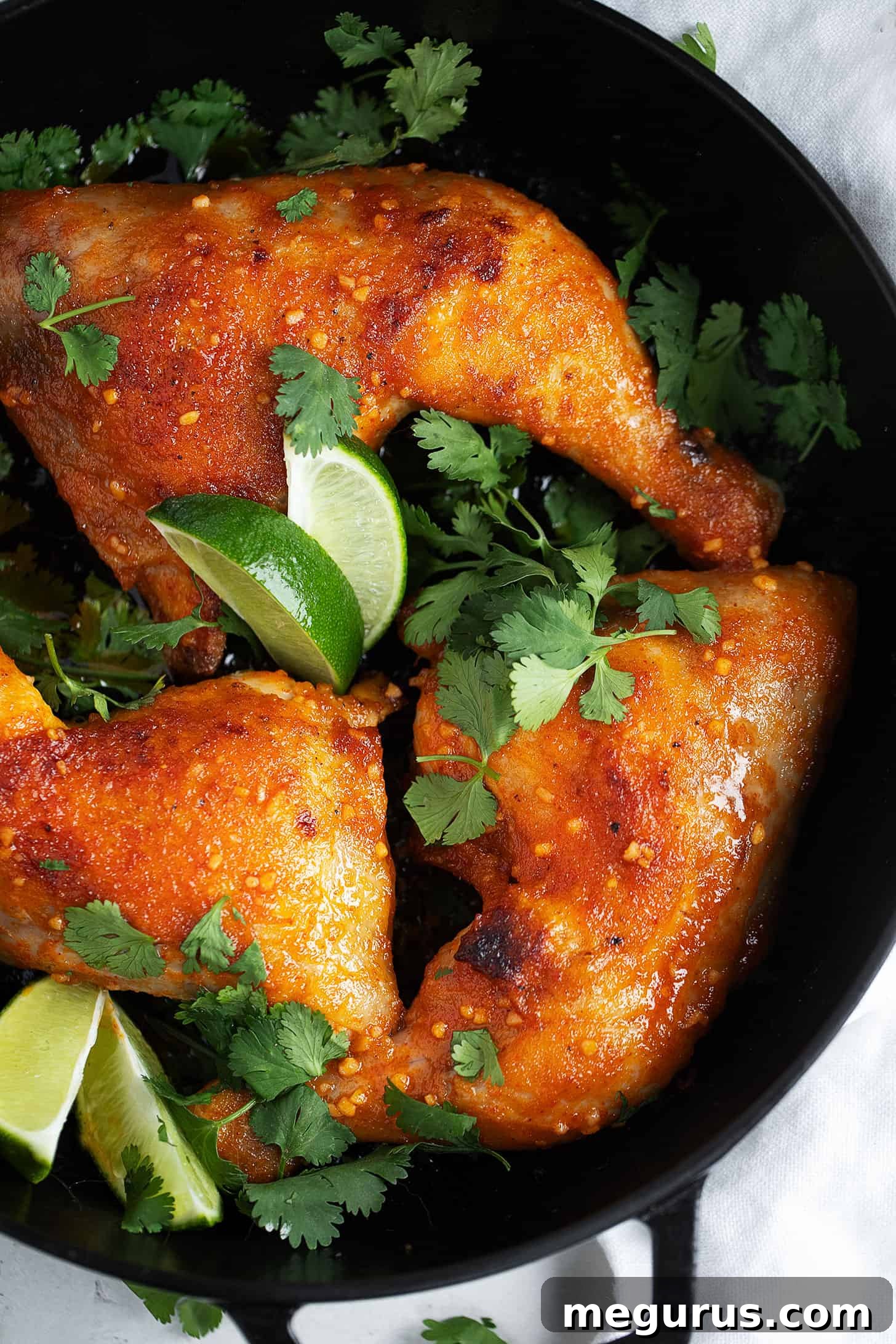Crispy, perfectly glazed Sriracha chicken legs resting in a skillet, showcasing their delicious finish with herbs.