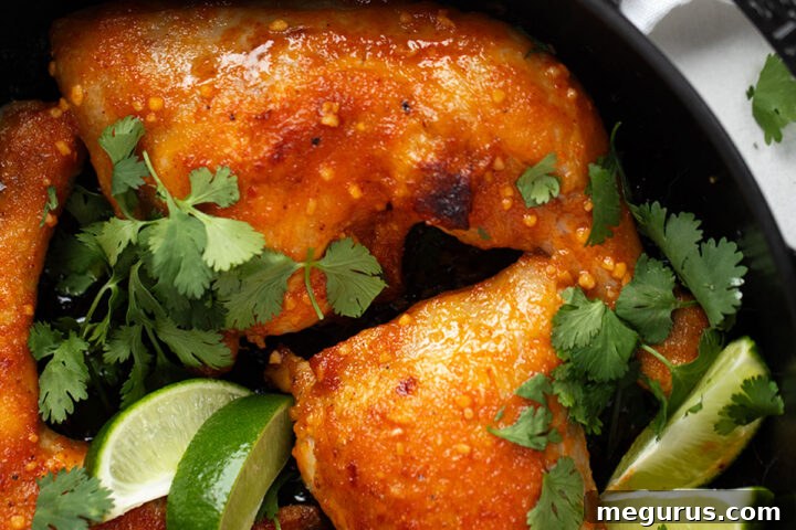 Close-up of golden Sriracha chicken legs in a baking dish, perfectly cooked and glistening, garnished with fresh cilantro.