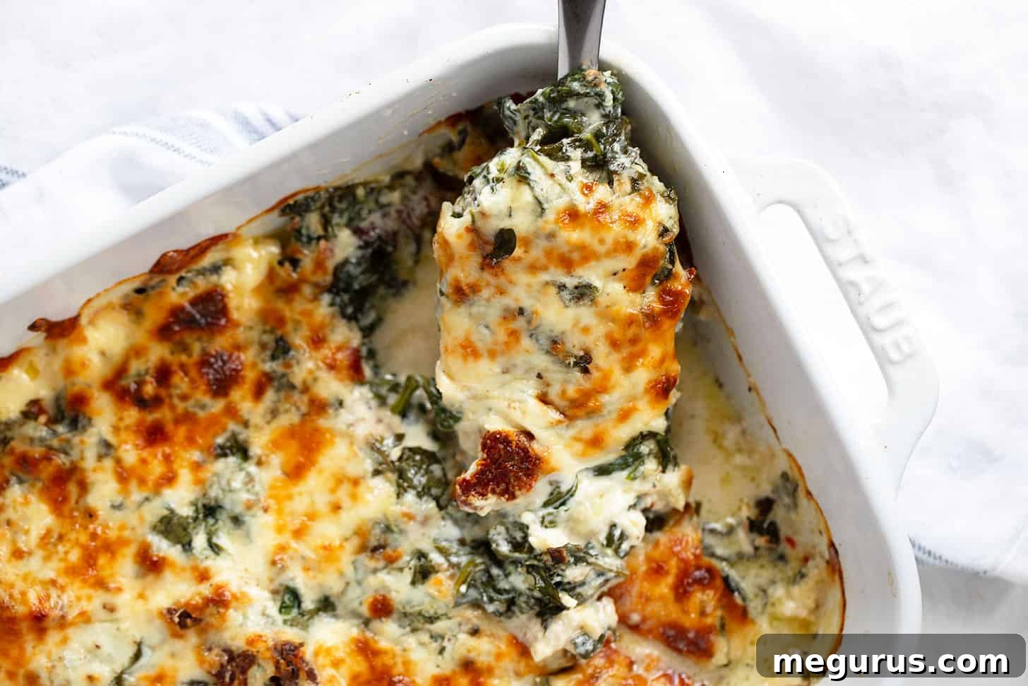 Baked Tuscan chicken in baking dish with spoon.