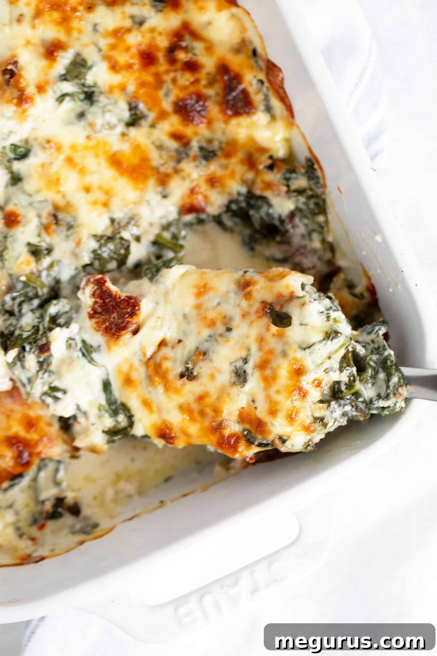 Baked Tuscan chicken in baking dish with spoon.