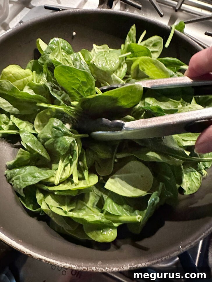 Wilting the spinach in a skillet.
