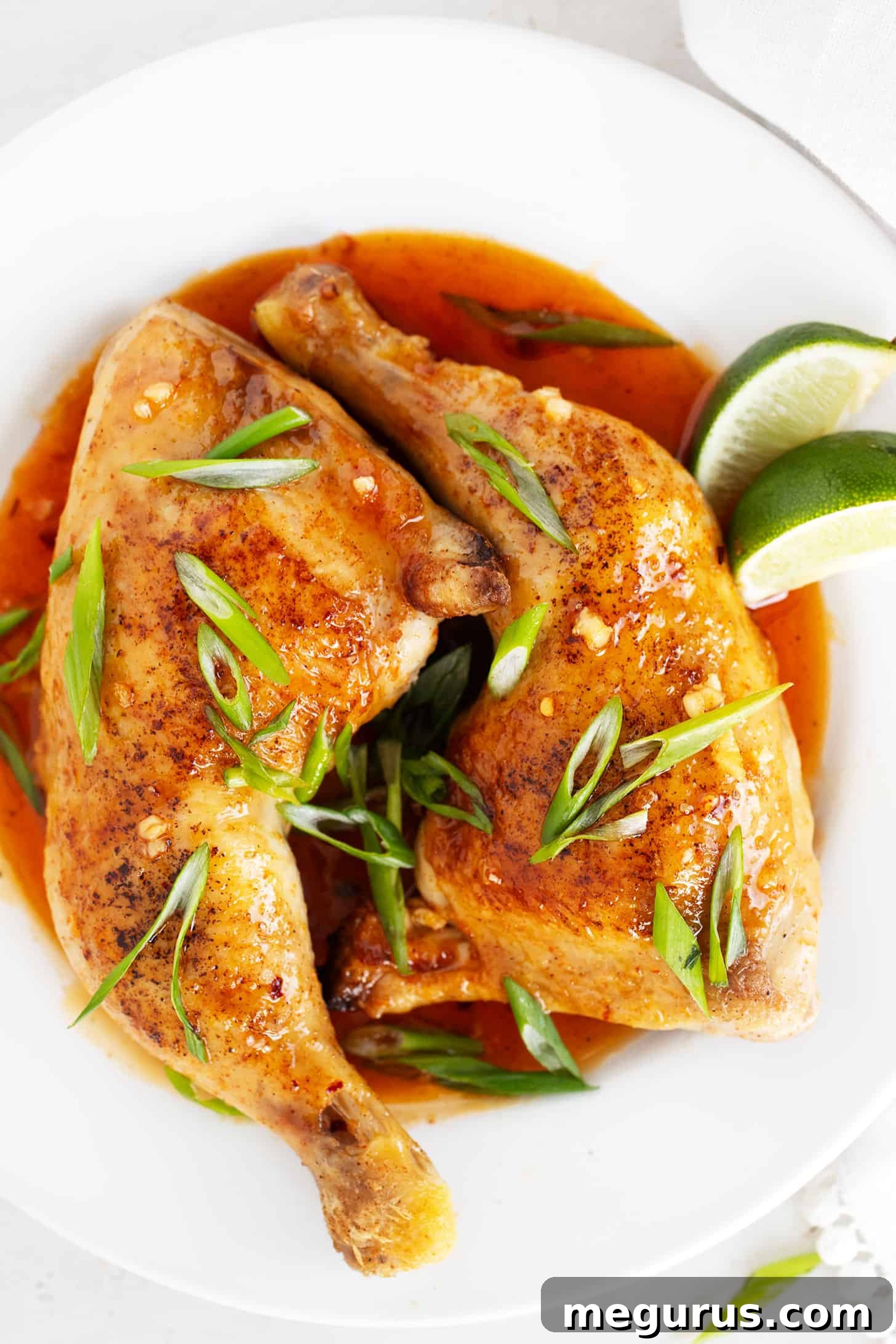 Hot honey glazed chicken legs, garnished with fresh green onion and lime, ready to serve.