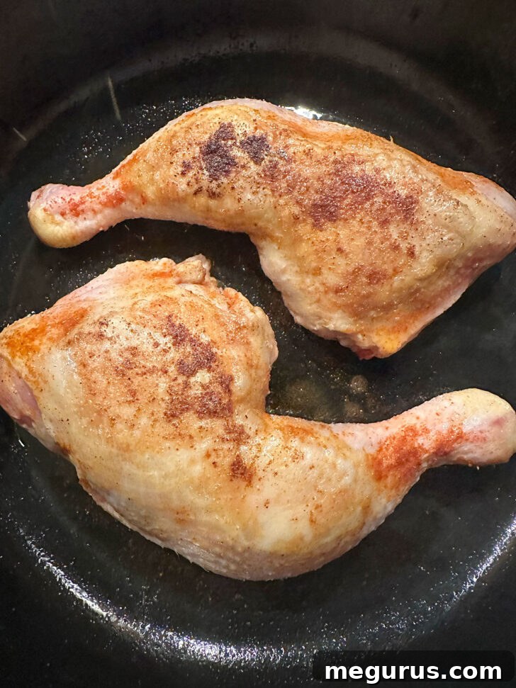 Chicken legs flipped, cooking briefly on the underside in the skillet.