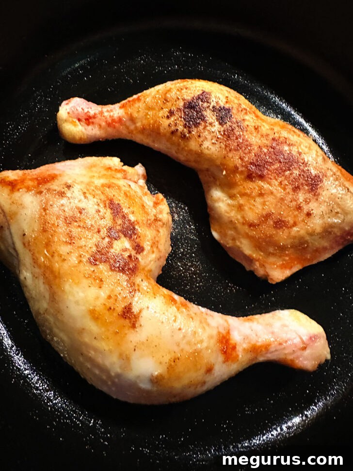 Seared chicken legs returned to a clean skillet, ready for oven baking.