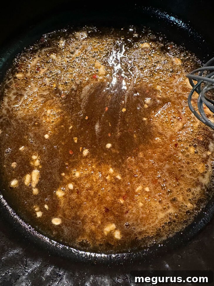Hot honey sauce bubbling and thickening in the skillet.