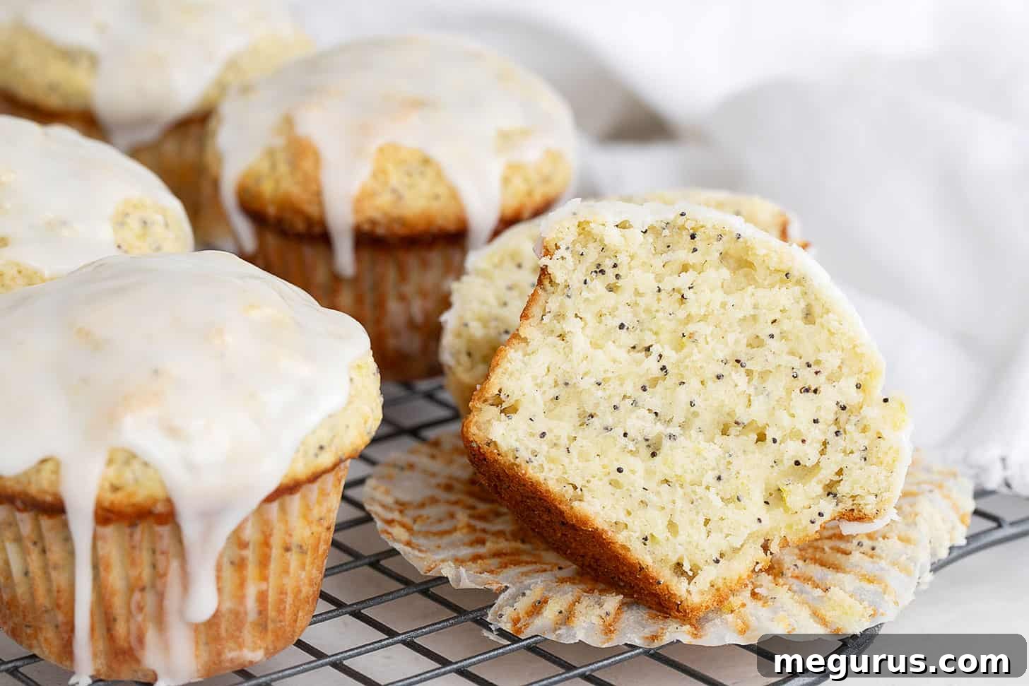Golden lemon poppy seed muffins on a cooling rack, freshly baked and ready for glazing.