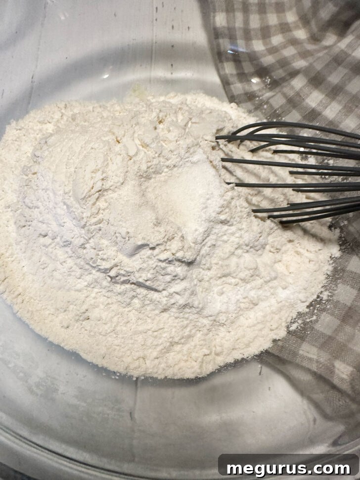 Dry ingredients, including flour, baking powder, baking soda, and salt, whisked together in a bowl.