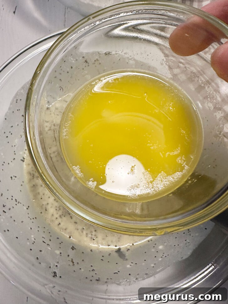 Cooled melted butter being added to the bowl of wet ingredients.