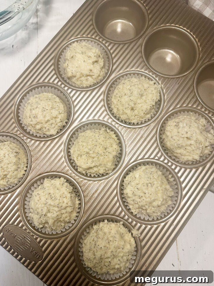 Muffin batter scooped into paper-lined muffin cups in a muffin tin.